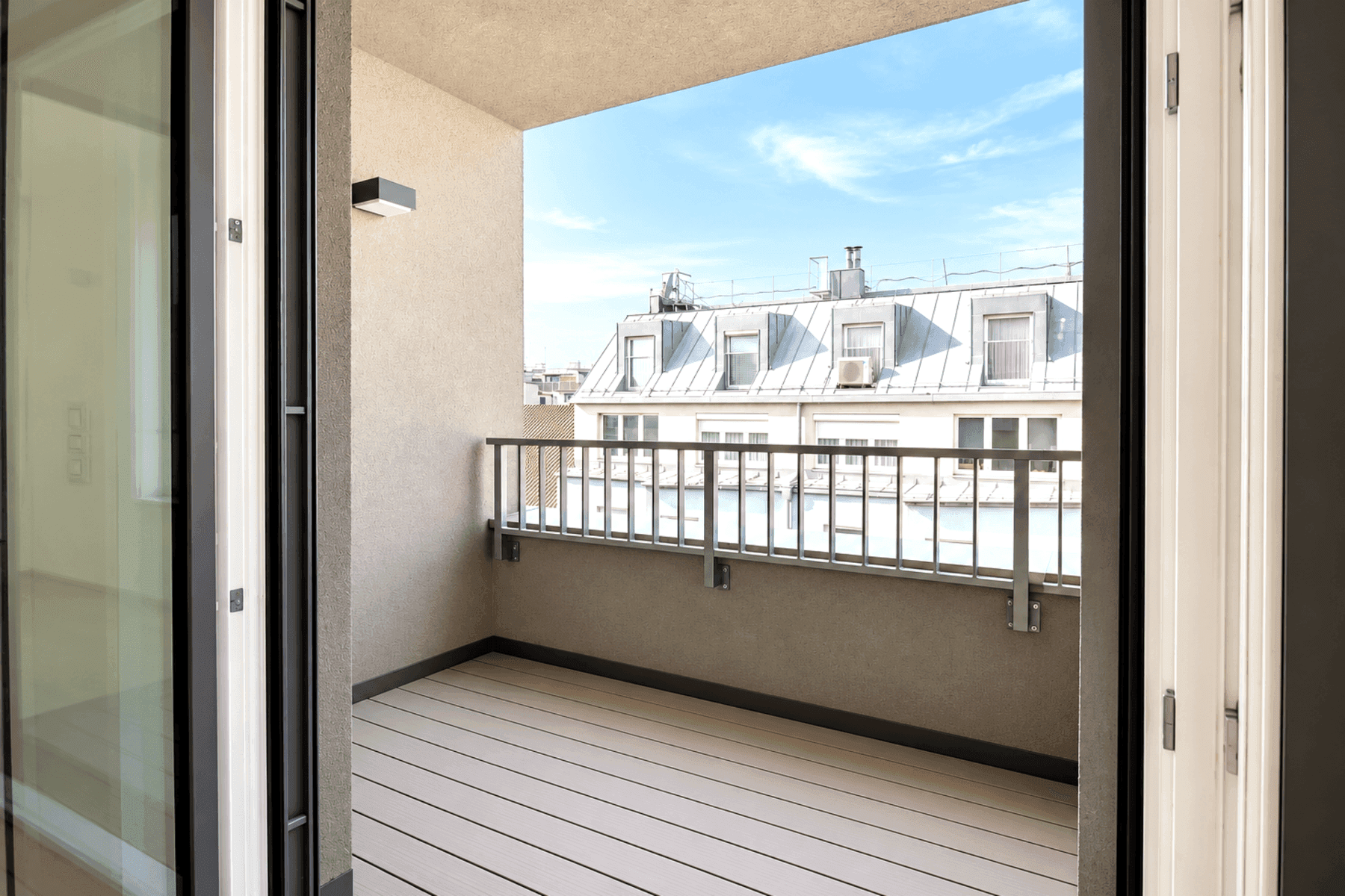 Leerer Balkon mit Holzboden und einem weiten Blick über die umliegenden Gebäude und Dächer.