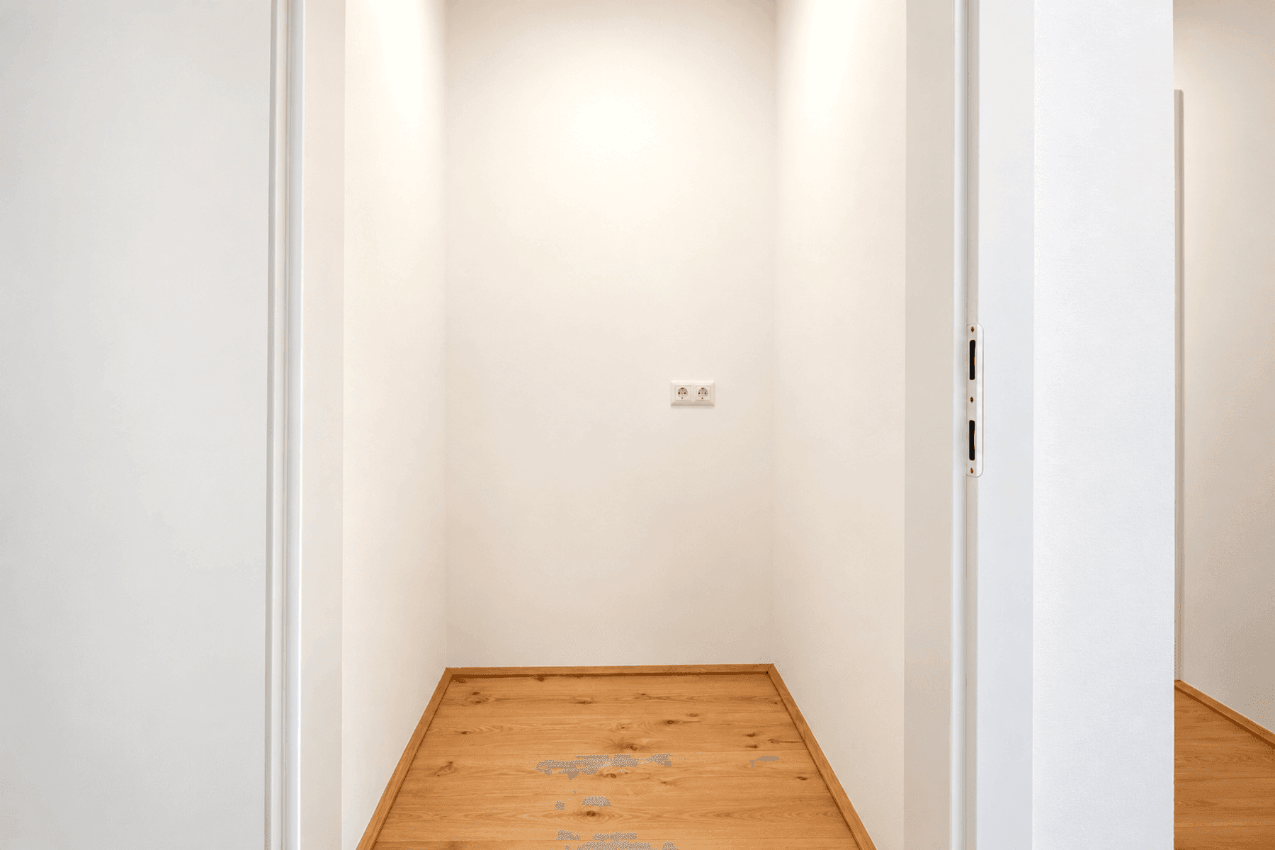 Praktischer Abstellraum oder Nische mit hellem Holzboden und Steckdosen für Geräte.