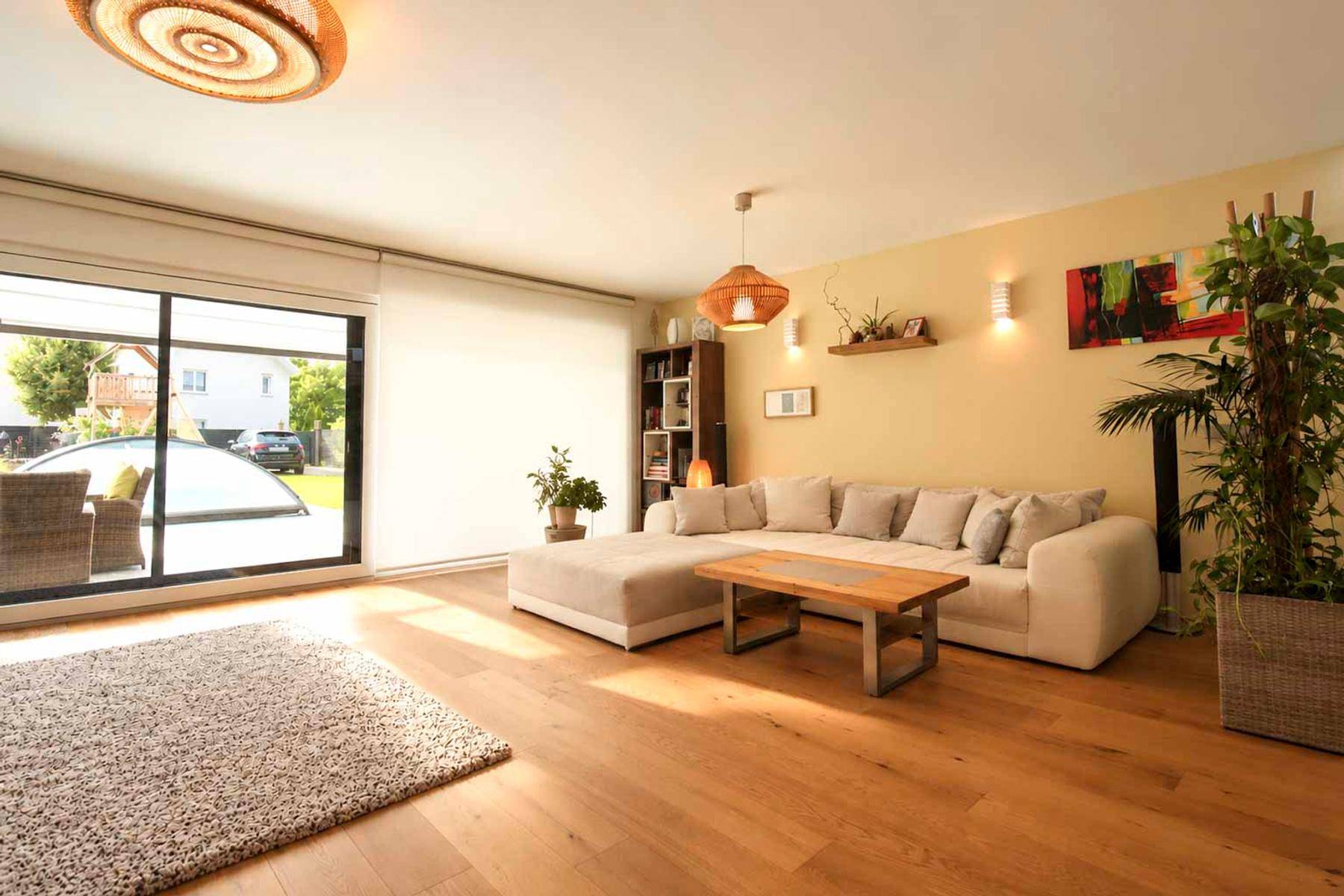 Gemütliches Wohnzimmer mit Holzboden, großem Sofa und Zugang zu einer Terrasse oder Garten.