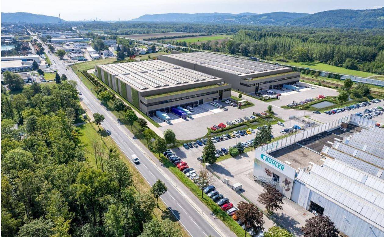 Luftaufnahme eines modernen Gewerbekomplexes mit begrünten Dächern, umgeben von viel Grün und Parkplätzen.