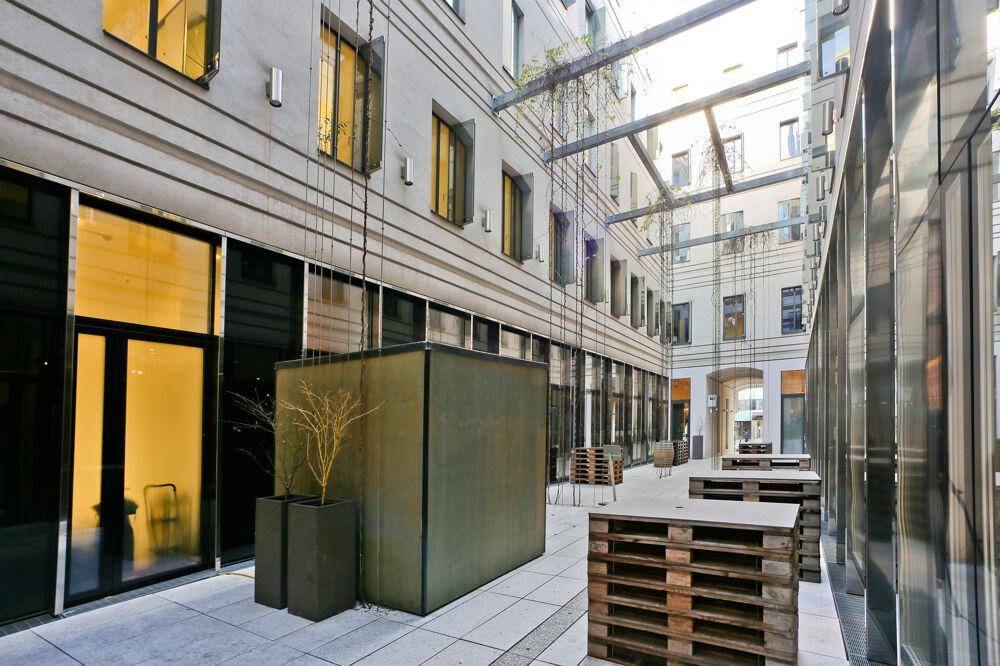 Moderner Innenhof mit minimalistischer Gestaltung, Sitzgelegenheiten aus Paletten und viel Tageslicht.