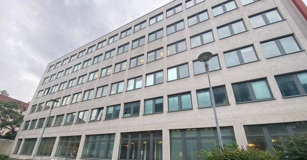 Seitliche Ansicht des Bürogebäudes mit einer möblierten Terrasse im Erdgeschoss.