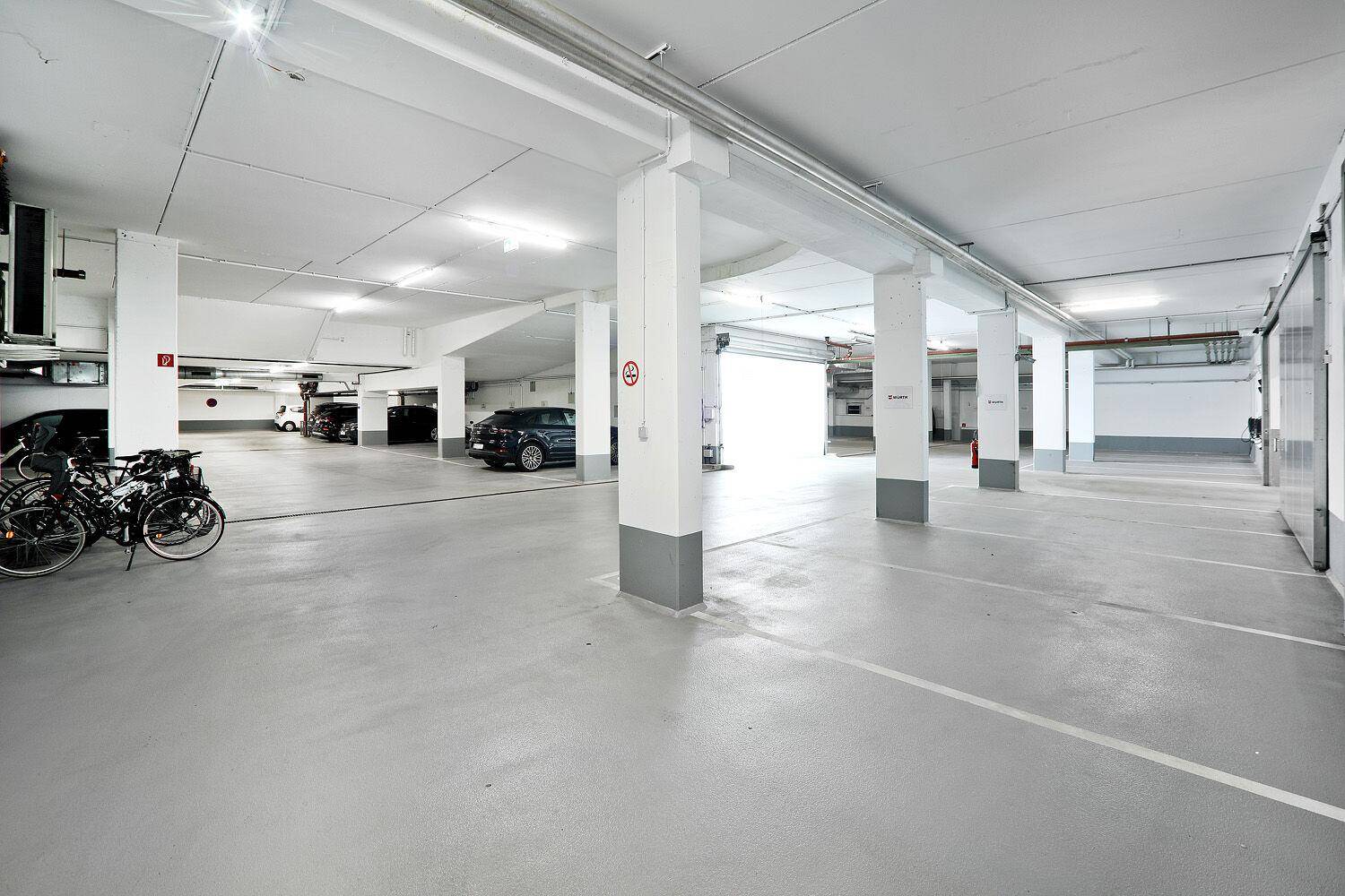 Geräumige Tiefgarage mit vielen Stellplätzen, Fahrrädern und einer hellen Beleuchtung.