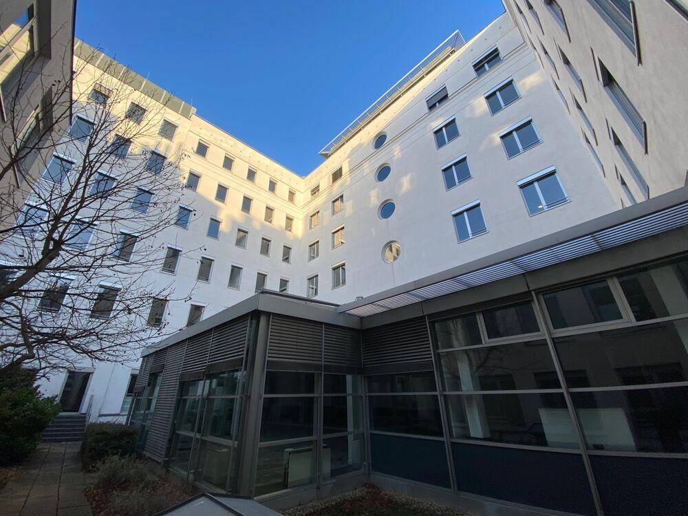Blick auf die moderne Gebäudearchitektur mit vielen Fenstern und einem Innenhof unter blauem Himmel.