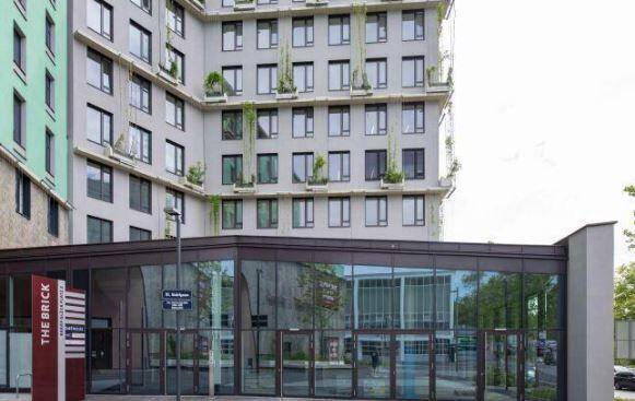 Nahaufnahme der modernen Gebäudefassade mit großflächiger Glasfront im Erdgeschoss und vielen Fenstern.