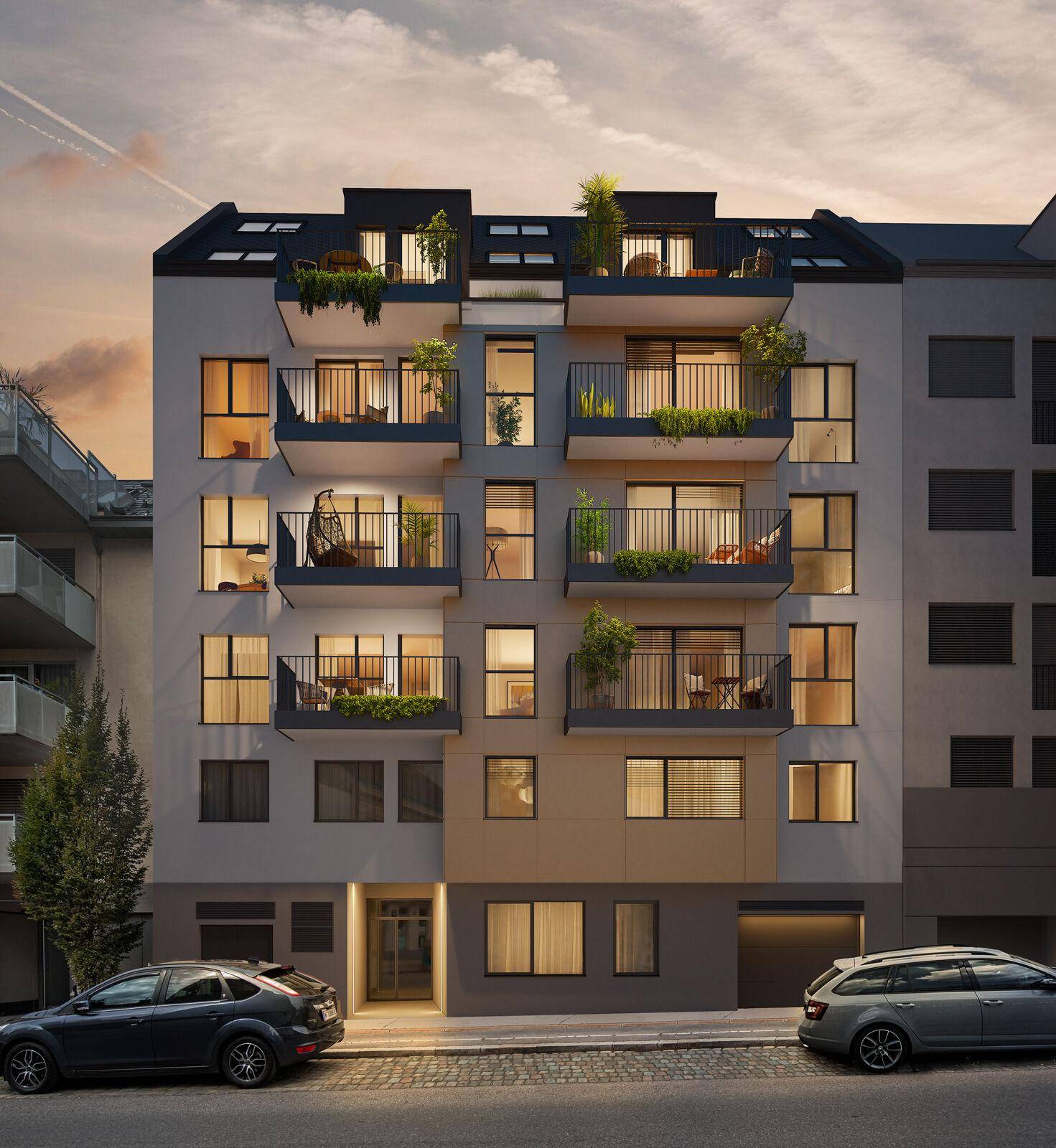 Abendliche Straßenansicht der modernen Wohnanlage mit beleuchteten Fenstern und Balkonen.