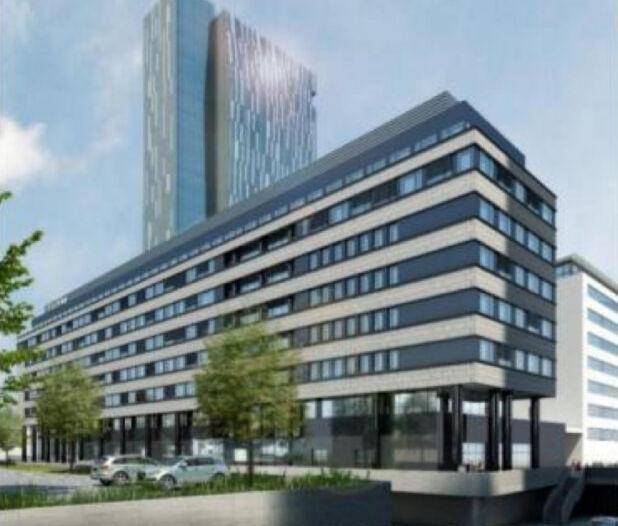 Ansicht des modernen Bürogebäudes mit Parkplätzen und einem weiteren Hochhaus im Hintergrund.