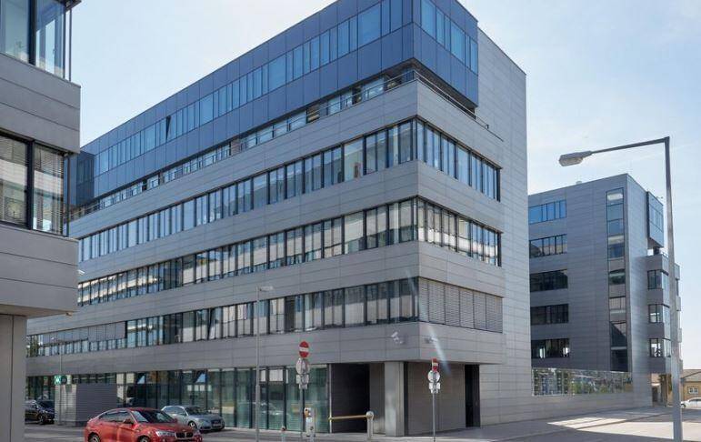 Eckansicht eines modernen Bürogebäudes mit vielen Fenstern und einer zeitgenössischen Fassadengestaltung.