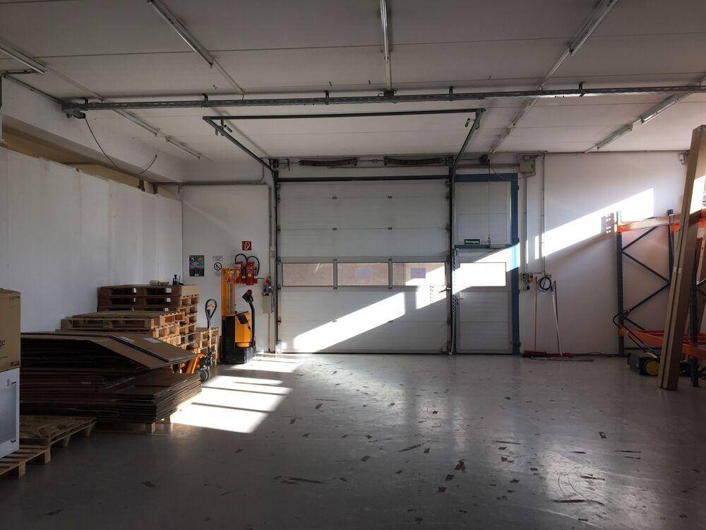 Industrieller Lagerraum mit Rolltor, Betonboden und natürlichem Lichteinfall durch die Türöffnung.