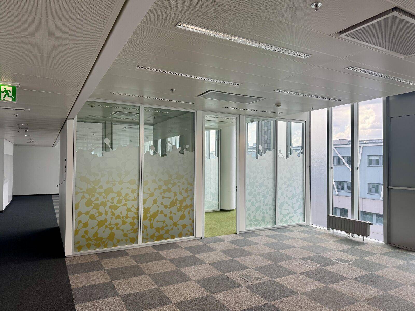 Modernes Büro mit kariertem Teppichboden und dekorativen Glaswänden, die für Privatsphäre sorgen.