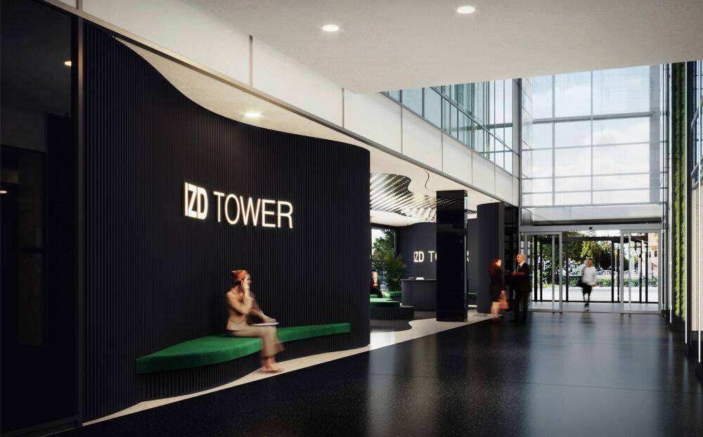 Geräumige, moderne Lobby mit dunklen Wänden, grünen Sitzbänken und viel Tageslicht durch große Fenster.