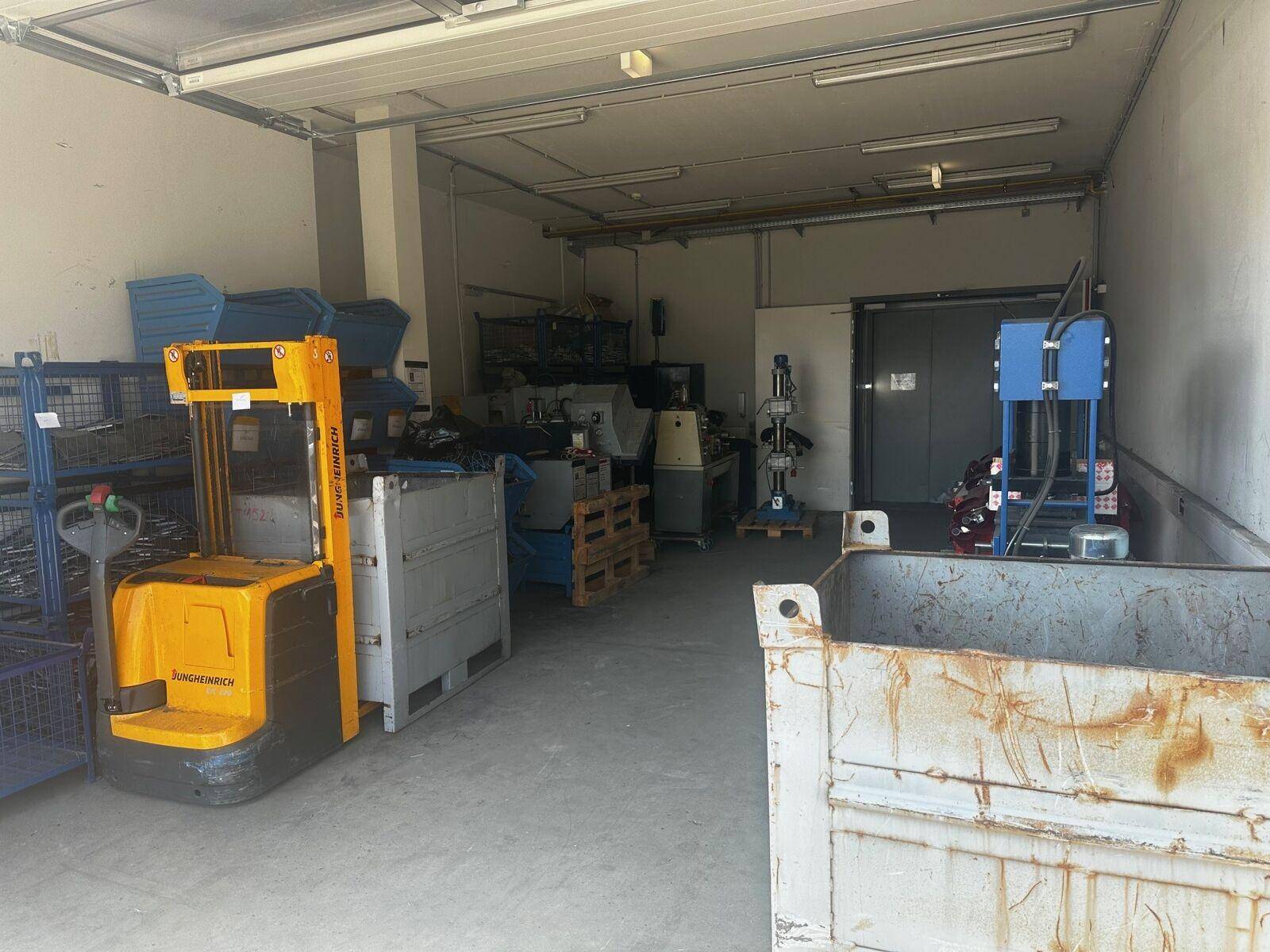 Lagerraum mit Gabelstapler, Regalen und verschiedenen Geräten, bereit für industrielle Nutzung.