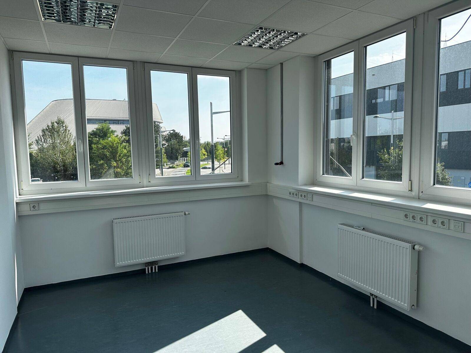 Helles Eckbüro mit großen Fenstern, die viel Tageslicht hereinlassen und einen Blick nach draußen bieten.