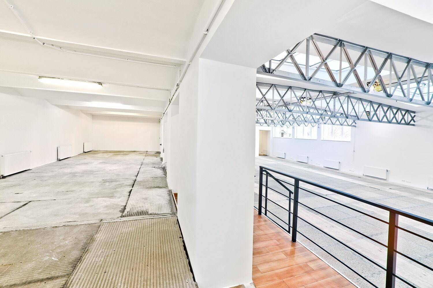 Blick auf einen großen Gewerberaum mit industriellen Elementen, hohen Decken und einer Galerie.