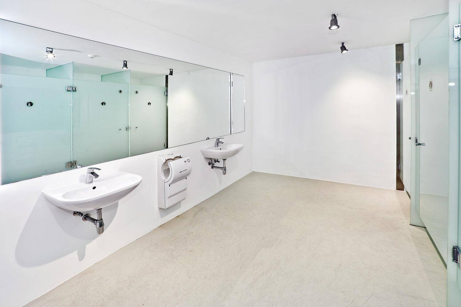 Heller, moderner Waschraum mit mehreren Waschbecken, großen Spiegeln und Handtrocknern.