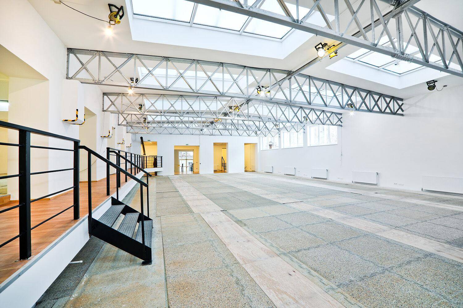Weitläufiger Gewerberaum mit industriellem Charme, großen Oberlichtern und einer Treppe zu einer erhöhten Ebene.