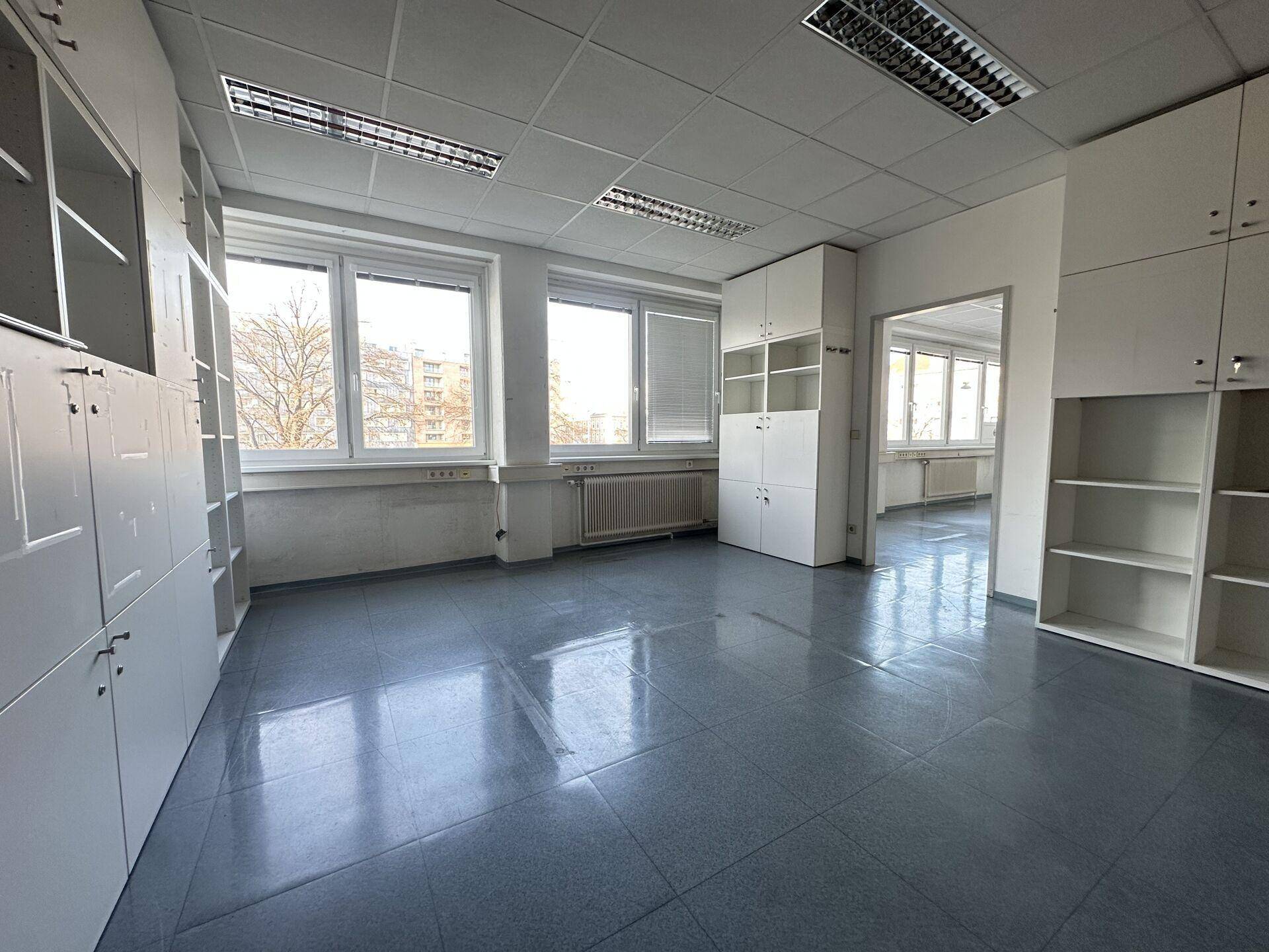Büro mit Einbauschränken und Regalen, großen Fenstern und viel Tageslicht, ideal für Lagerung.