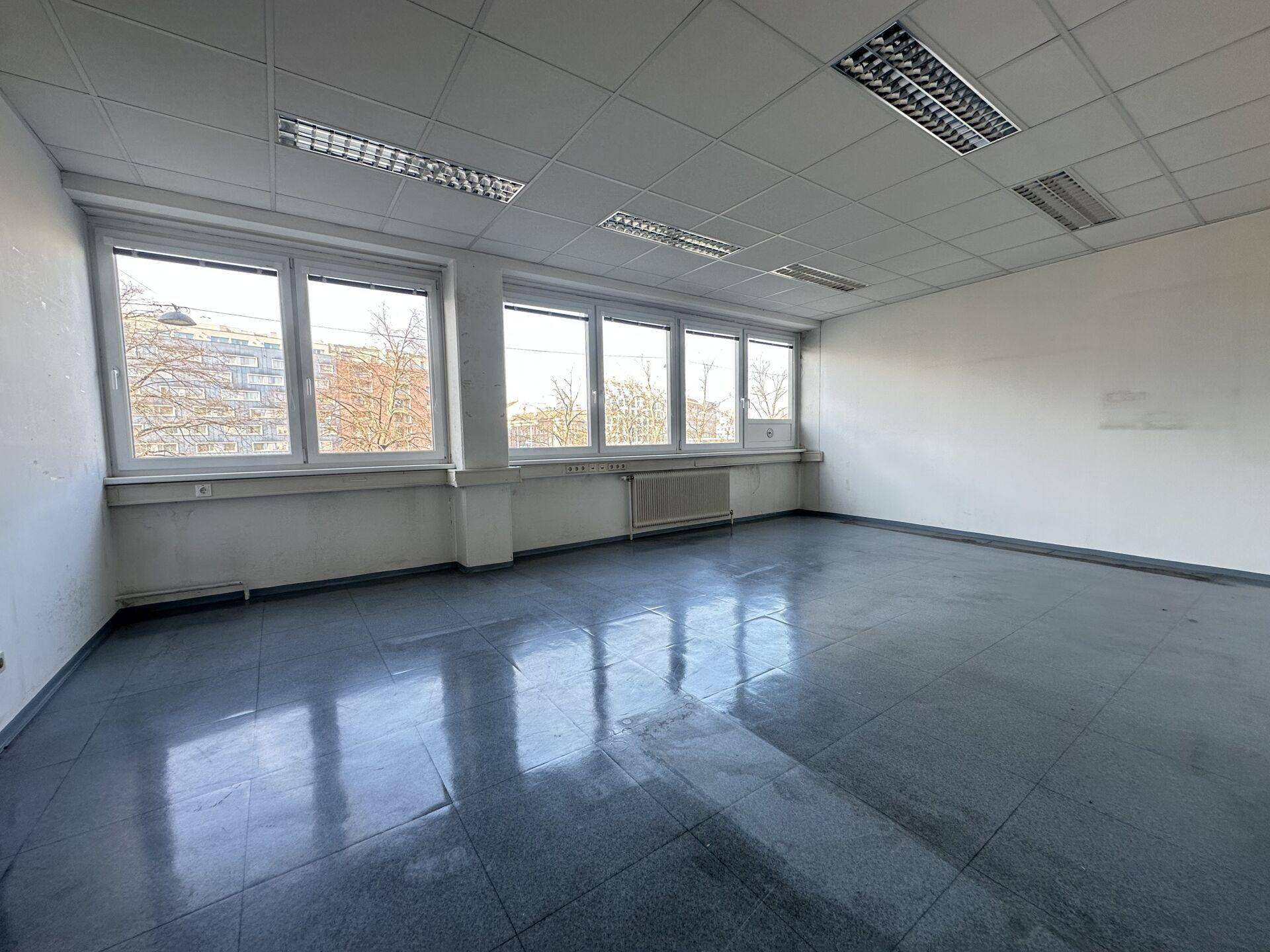 Leeres Büro mit großen Fenstern, die einen weiten Blick auf die Umgebung und Bäume ermöglichen.