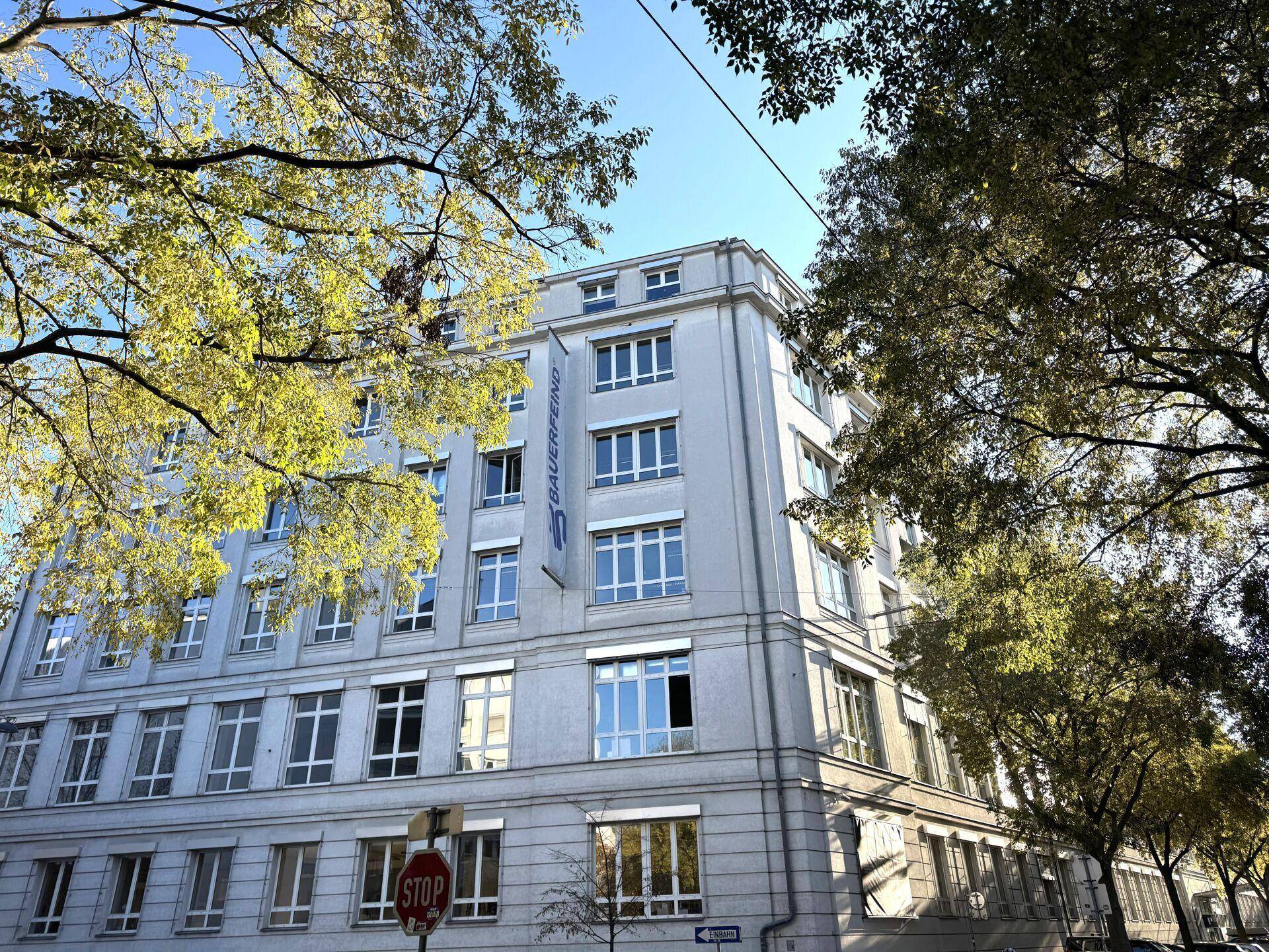 Die Ecke eines modernen Bürogebäudes mit vielen Fenstern und einem klaren blauen Himmel.