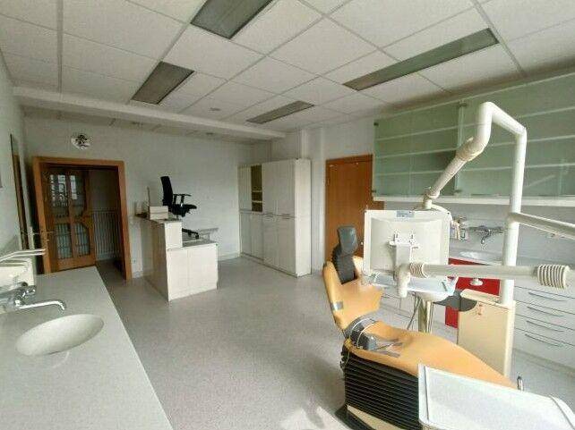 Behandlungszimmer mit zahnmedizinischem Stuhl, Waschbecken und Schränken, bereit für den Betrieb.