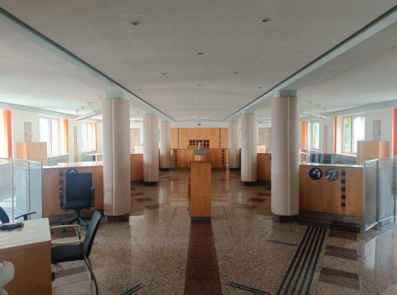 Großer, offener Bürobereich mit vielen Säulen, Schreibtischen und glänzendem Steinboden.