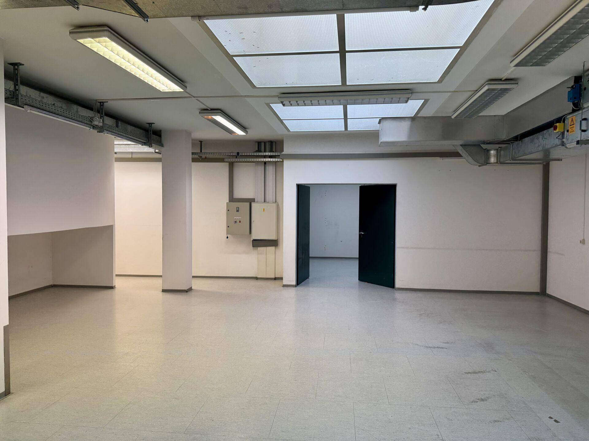 Geräumiger Lagerraum mit Fliesenboden, sichtbaren Lüftungsrohren und Deckenbeleuchtung.