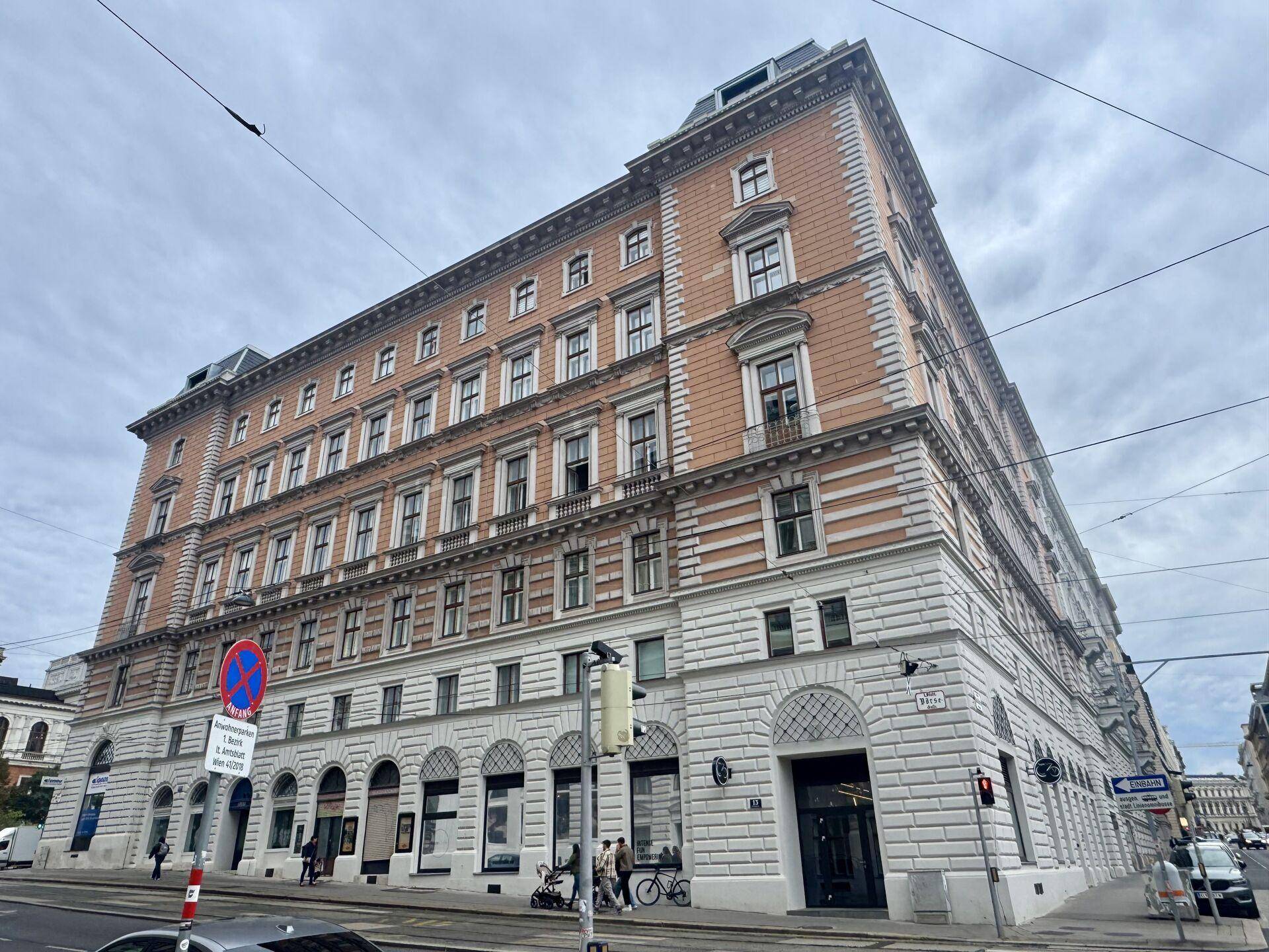 Eindrucksvolles Eckgebäude mit klassischer Architektur und vielen Fenstern in einer städtischen Umgebung.