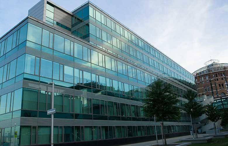 Weitläufige Glasfassade eines modernen Bürokomplexes mit vielen Fenstern und klaren Linien, die das Tageslicht optimal nutzen.
