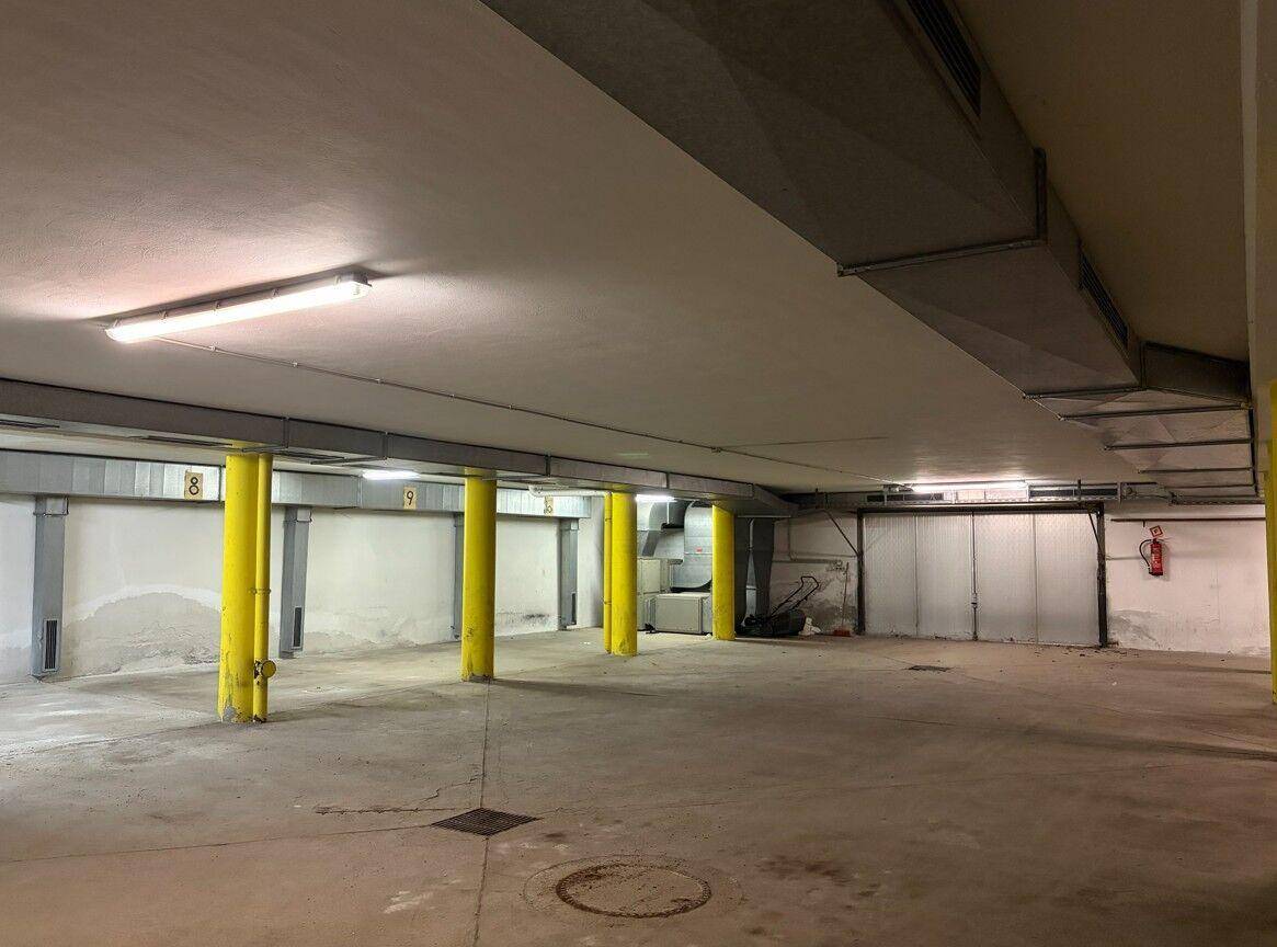 Geräumige Tiefgarage mit gelben Stützpfeilern und Betonboden, gut beleuchtet.