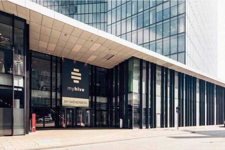 Der Eingangsbereich eines modernen Bürogebäudes mit großer Glasfront und dem "myhive" Logo.