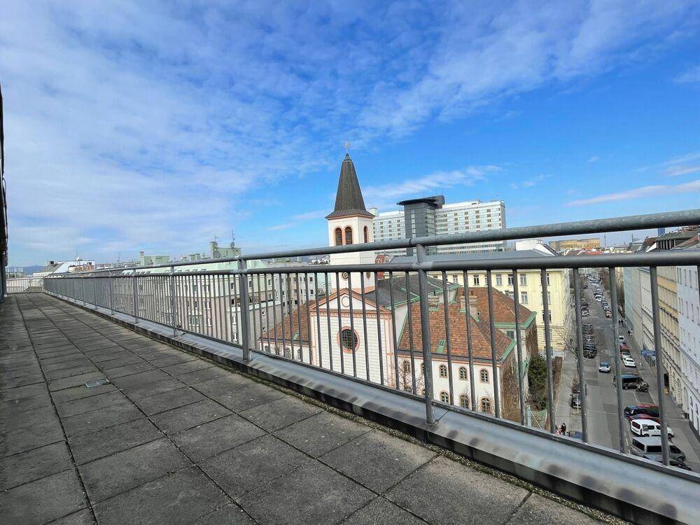 Dachterrasse mit weitem Blick über die Stadt, eine Kirche und belebte Straßen.