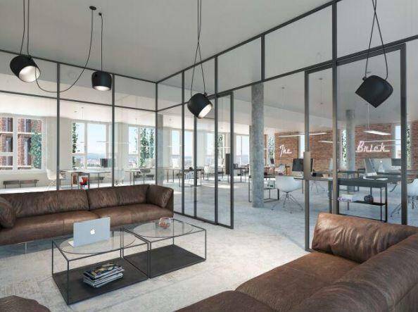 Moderner Bürobereich mit Ledersofas, Glastrennwänden und Blick auf weitere Arbeitsplätze.