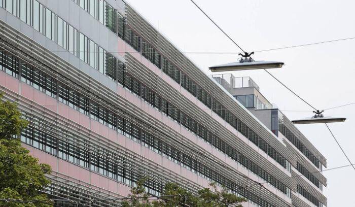 Moderne Gebäudefassade mit horizontalen Sonnenschutzlamellen und großen Fensterfronten.