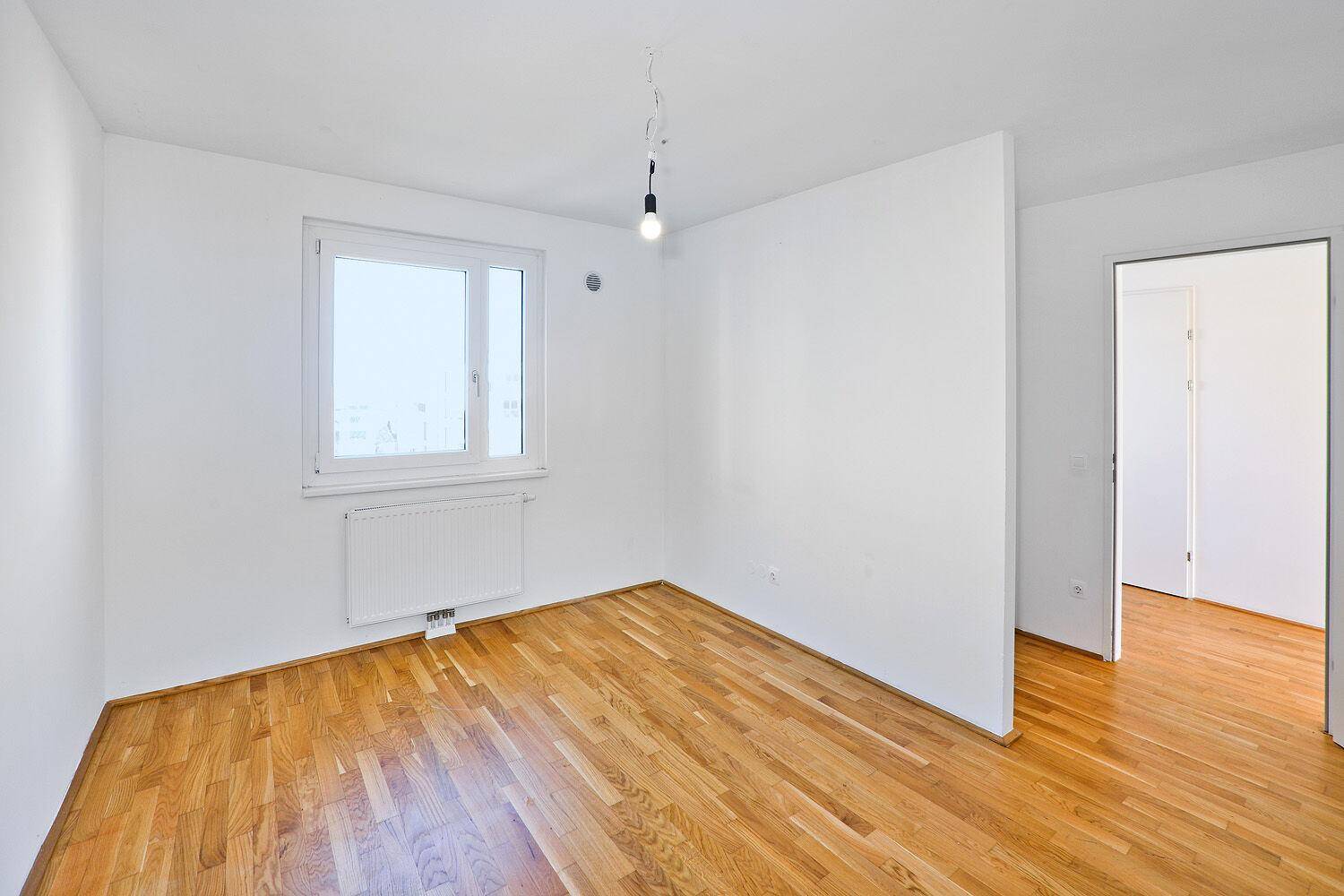 Geräumiges Schlafzimmer mit Parkettboden und weiß gestrichenen Wänden, bereit zur Einrichtung.