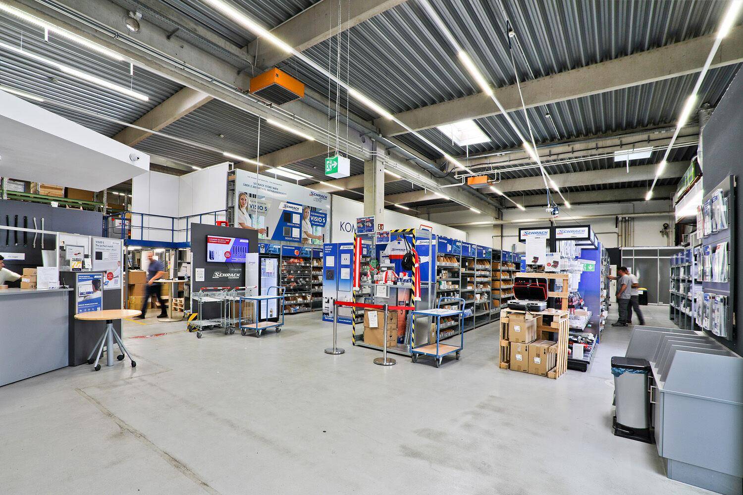 Geräumiger Verkaufsraum mit Produktregalen, Ausstellungsflächen und industrieller Deckenkonstruktion.