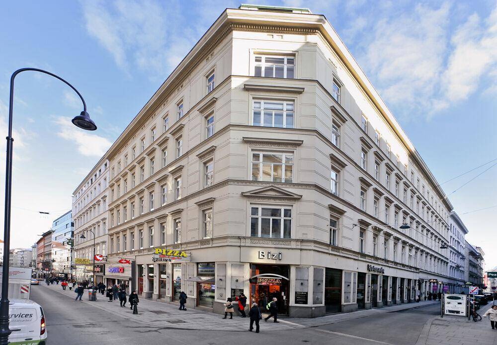 Historisches Eckgebäude mit klassischer Architektur und vielen Fenstern an einer belebten Stadtstraße.
