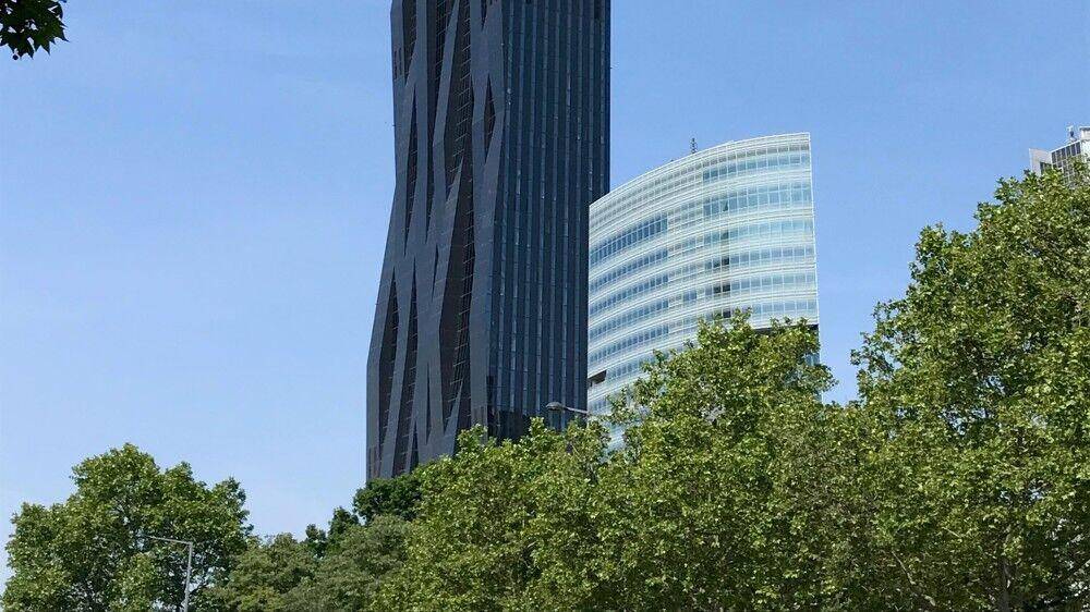 Hohe moderne Gebäude mit einzigartiger Fassadengestaltung, umgeben von üppigem Grün und Bäumen.