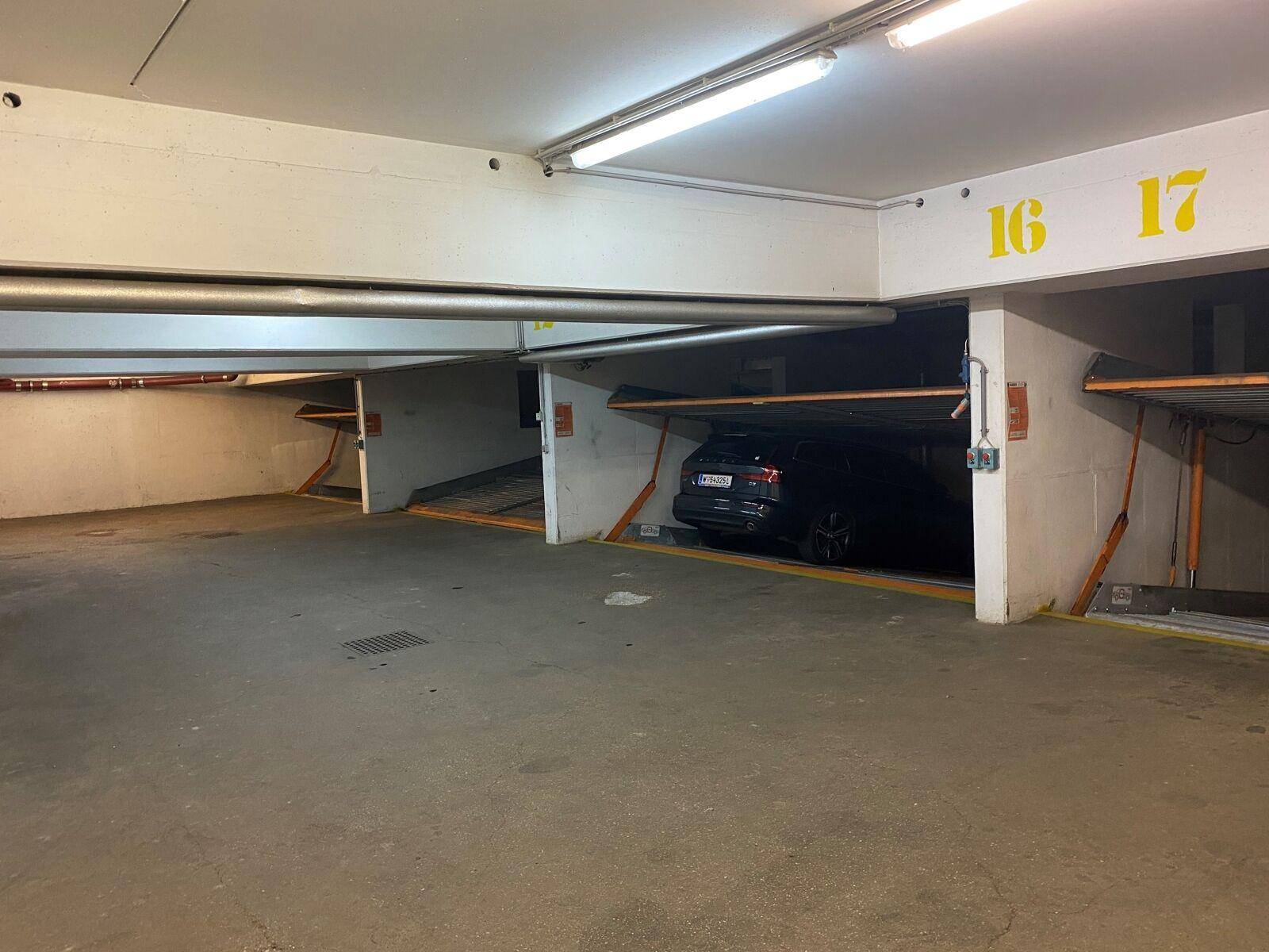 Tiefgarage mit nummerierten Stellplätzen und einem geparkten Auto in einer modernen Anlage.