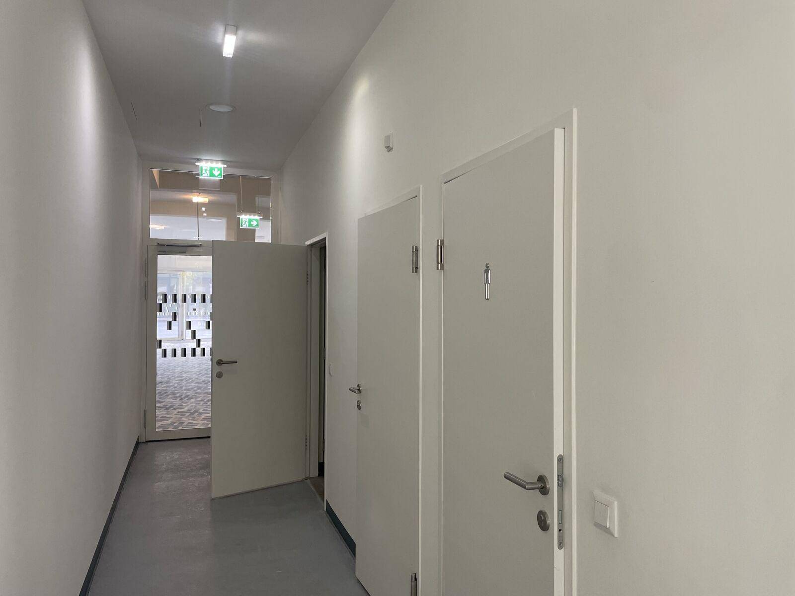 Heller Flur mit mehreren Türen und modernen Deckenleuchten, der zu verschiedenen Räumen führt.