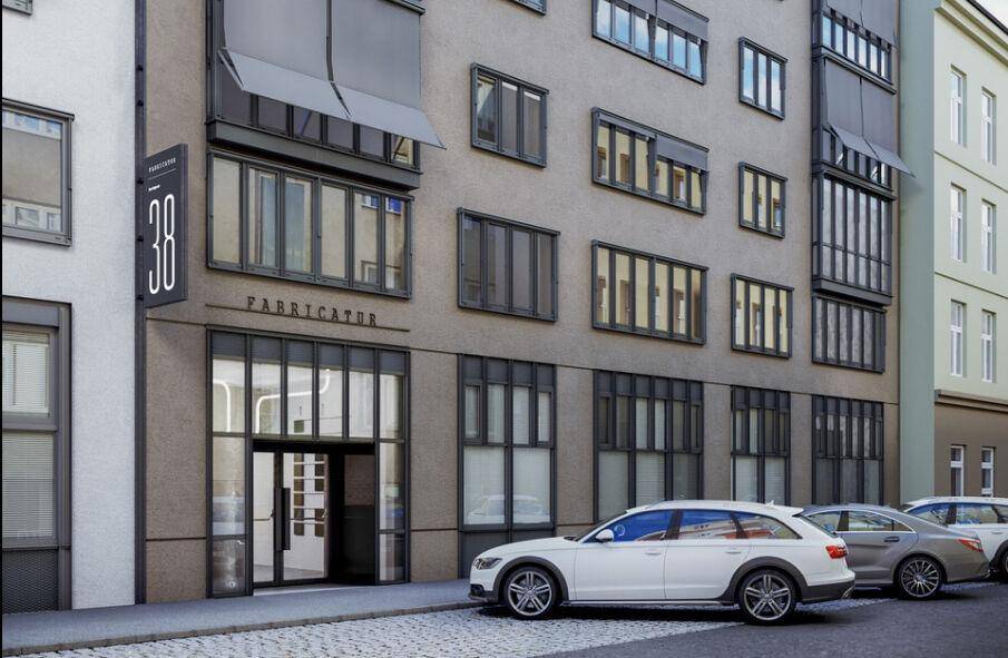 Moderne Gebäudefassade mit großen Fenstern und stilvollem Eingangsbereich an einer Straße.
