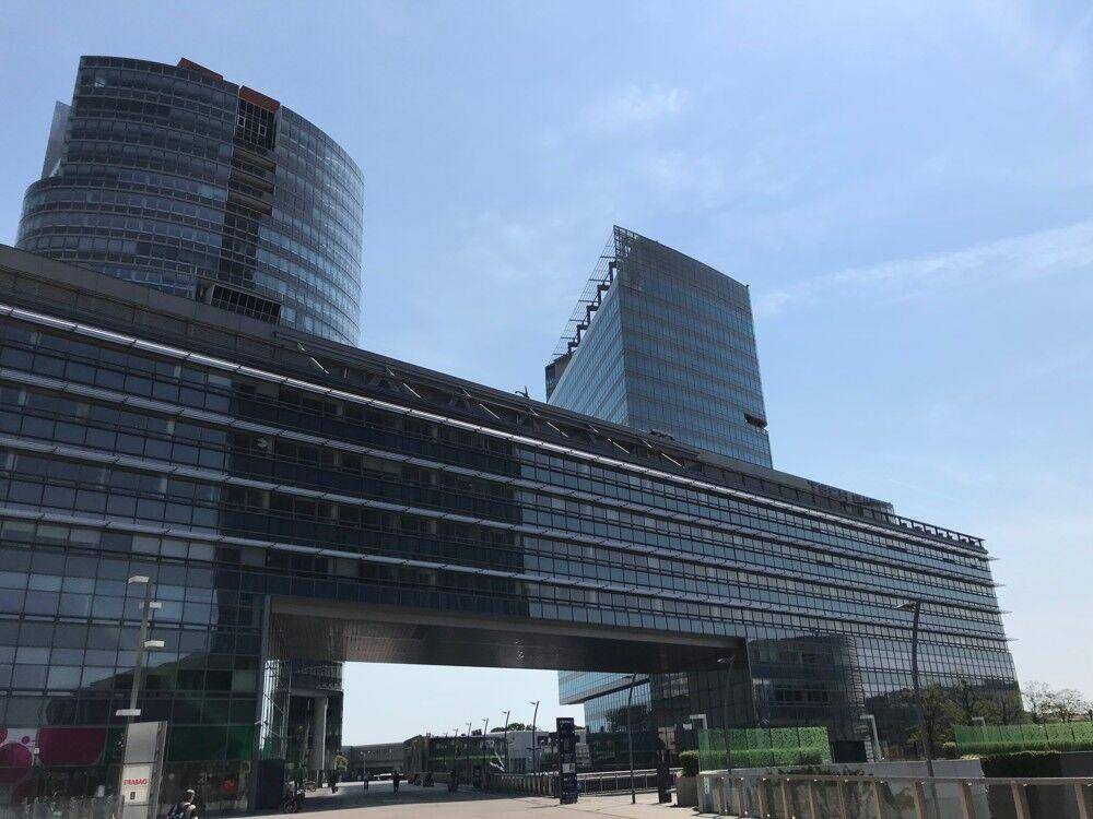 Moderne Bürogebäude mit Glasfassaden und einem markanten Durchgang unter einem der Türme.
