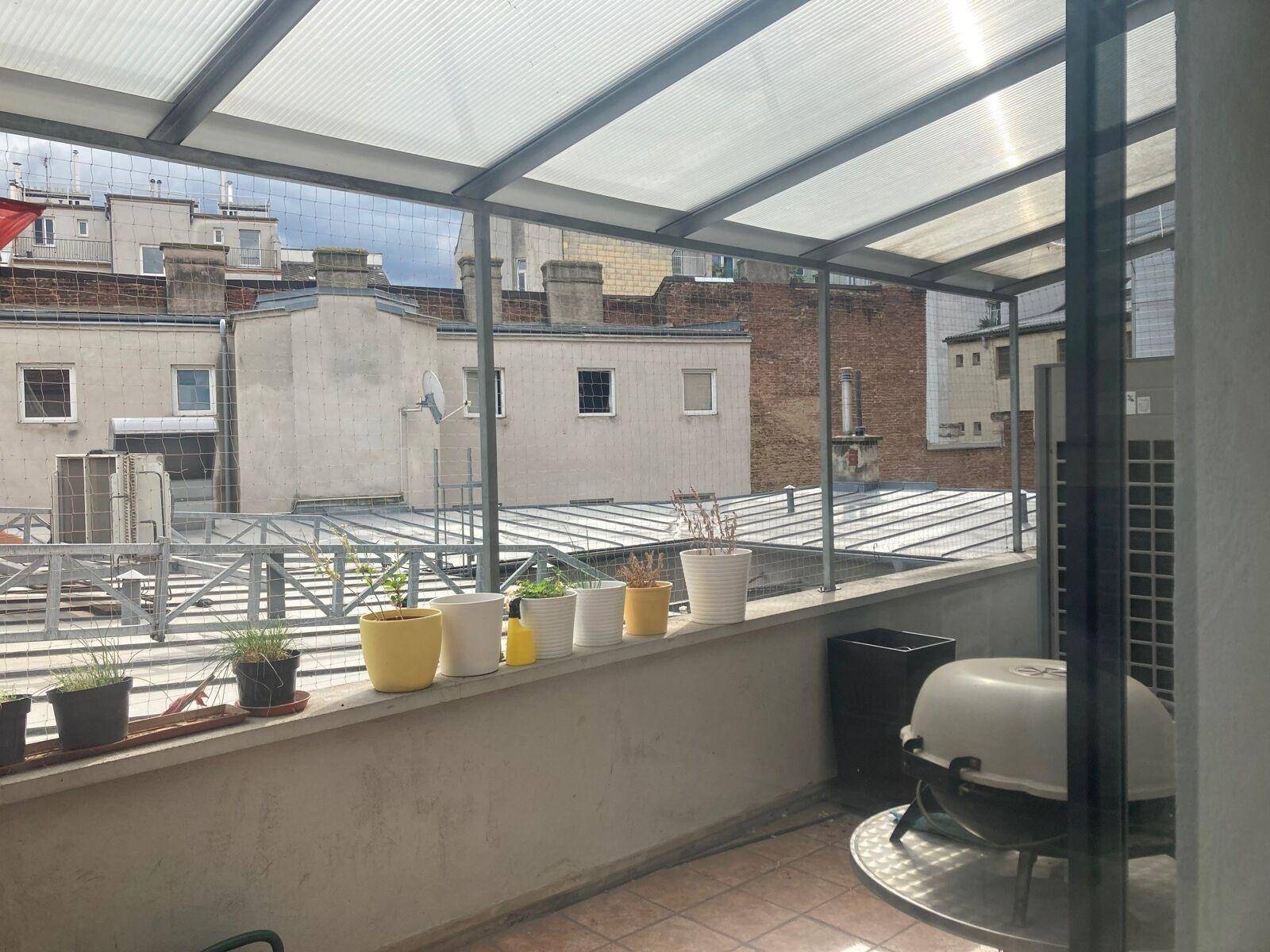 Überdachte Loggia mit Pflanzen und Blick auf die umliegenden Gebäude der Stadt.