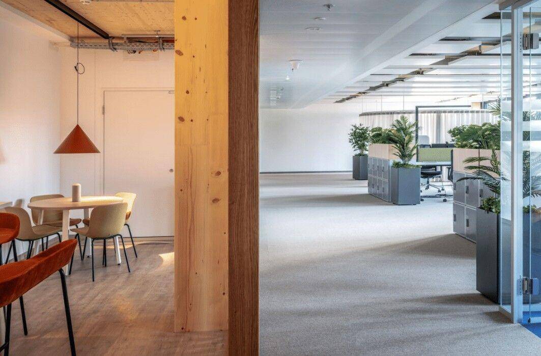 Funktionales Büro mit Holzelementen, Teppichboden und Glasabtrennungen, bietet flexible Arbeitsbereiche.