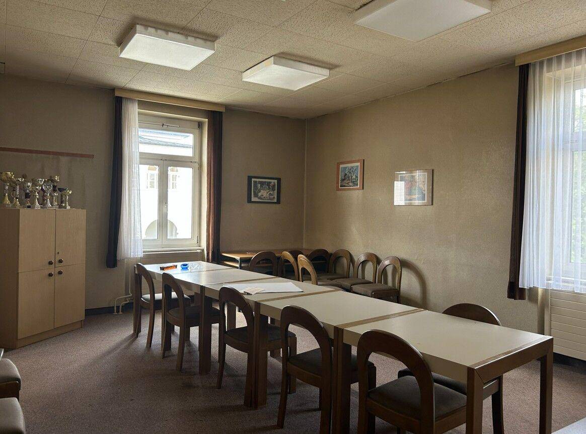 Besprechungsraum mit mehreren Tischen und Stühlen, ausgestattet für Konferenzen oder Schulungen.