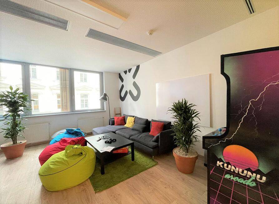 Entspannungsbereich mit Sofa, Sitzsäcken, Pflanzen und einem Arcade-Automaten für Mitarbeiter.