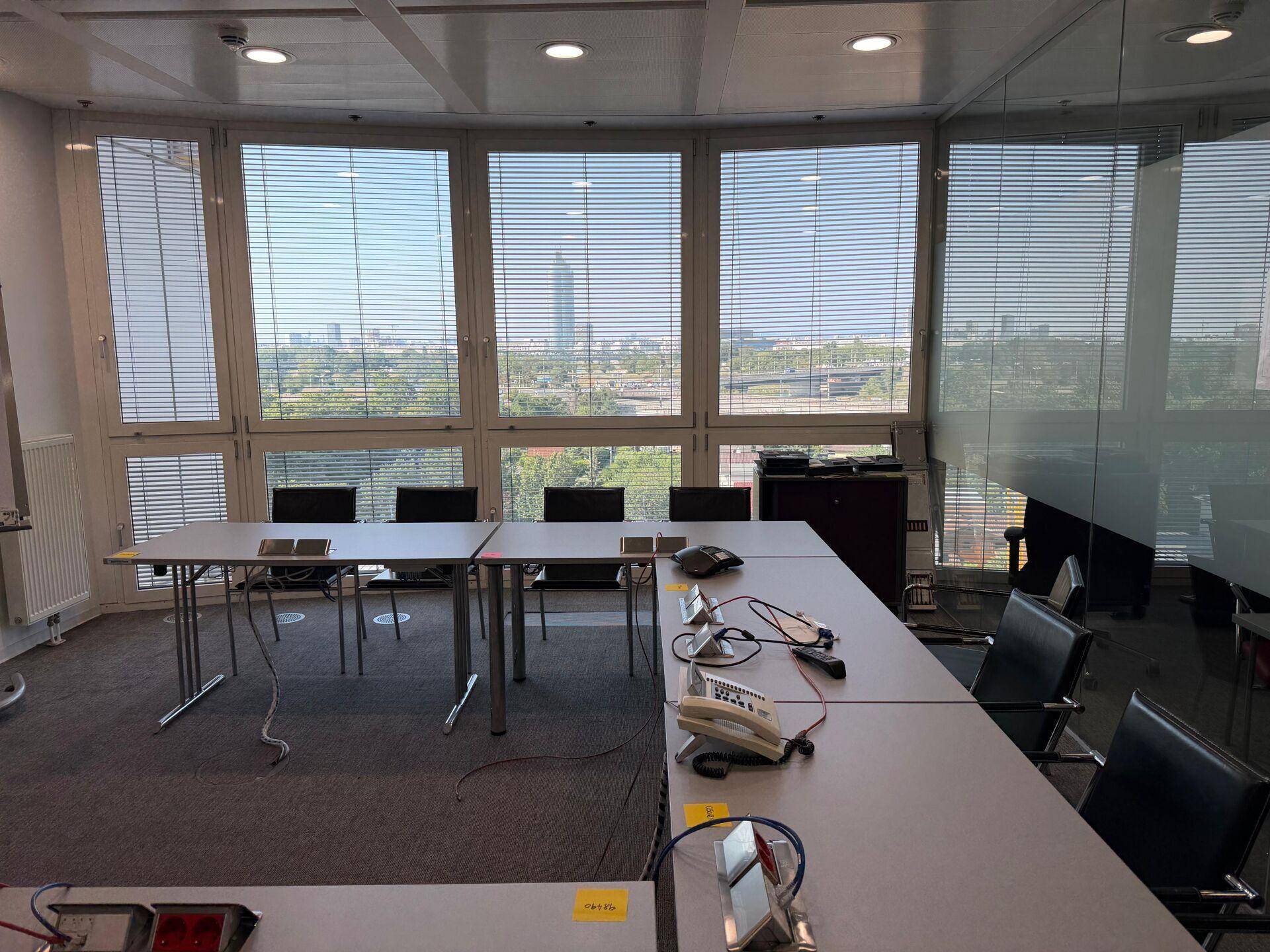 Großer Konferenzraum mit langen Tischen, vielen Stühlen und weitem Stadtblick.