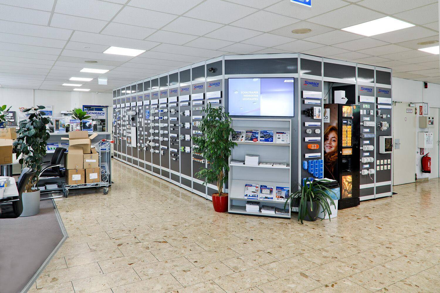 Heller Verkaufsraum mit Produktpräsentationen und gefliestem Boden in einem modernen Gebäude.