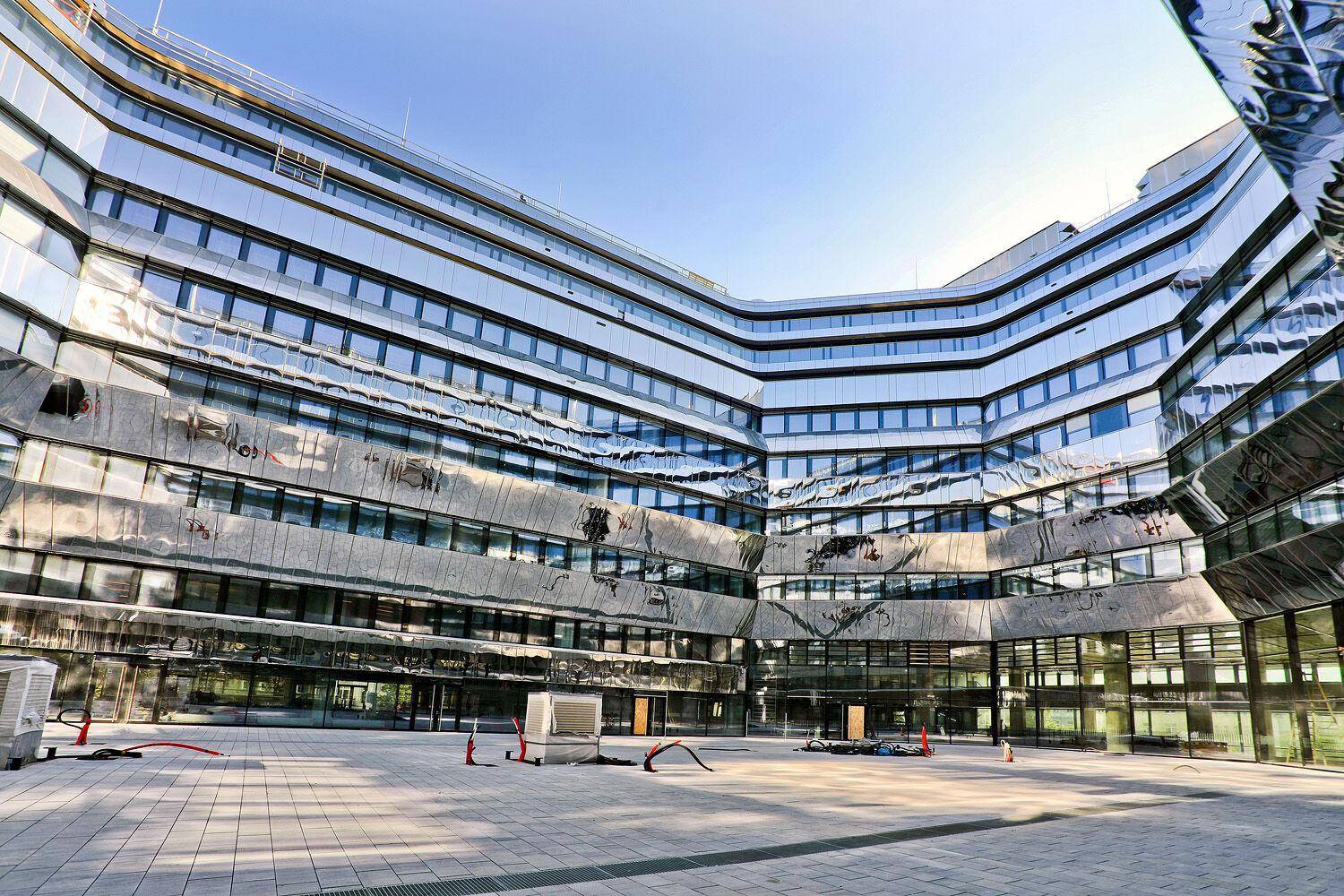 Beeindruckende moderne Architektur mit einer geschwungenen Glasfassade und einem weitläufigen Innenhof.