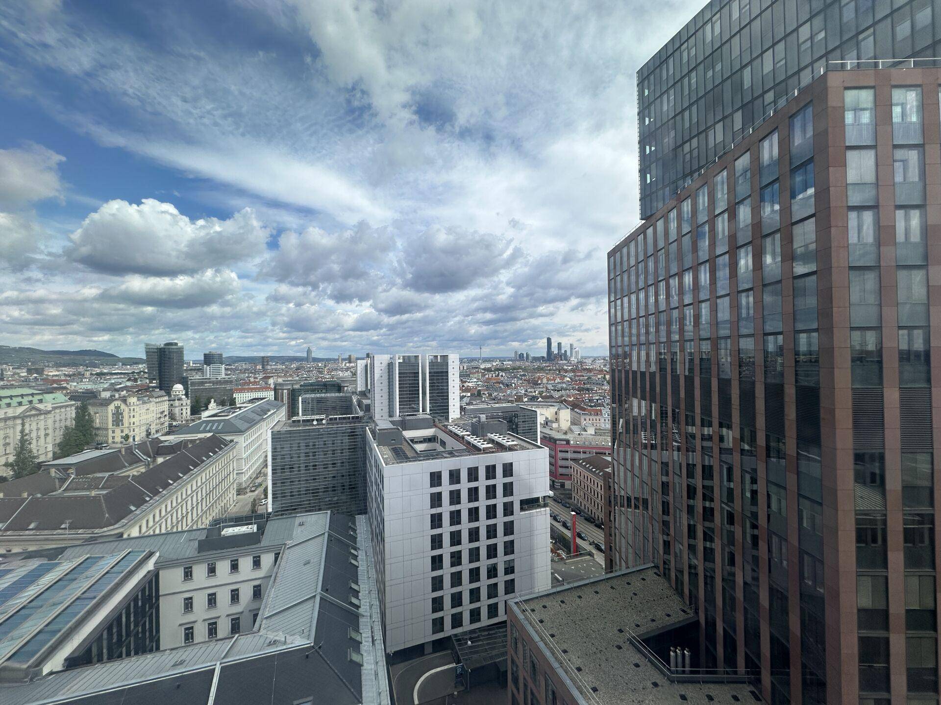 Weitblick über die Stadt mit einer Mischung aus modernen Glasfassaden und traditioneller Architektur unter blauem Himmel.
