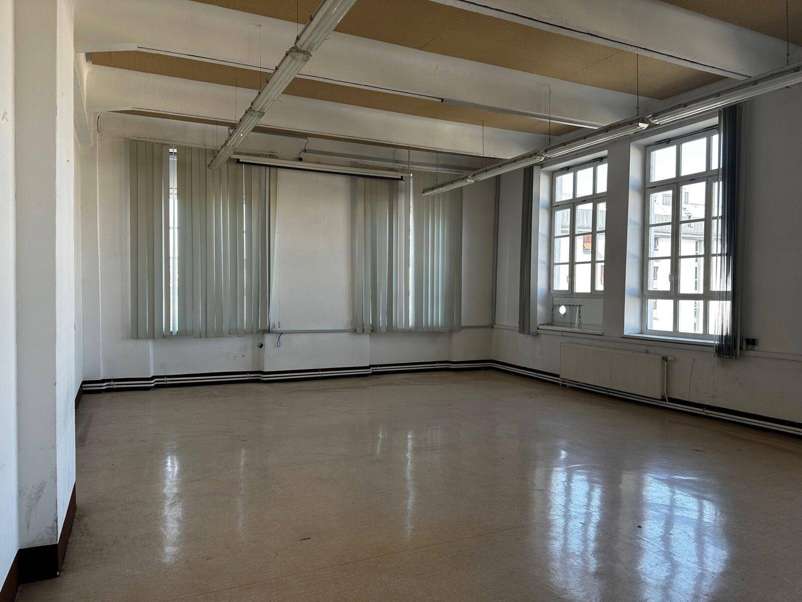 Geräumiger Innenraum mit großen Fenstern und einem Projektionsschirm, ideal für Besprechungen oder Schulungen.